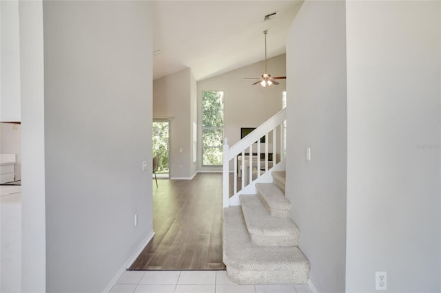 staircase featuring hardwood / wood-style floors, high vaulted ceiling, and ceiling fan