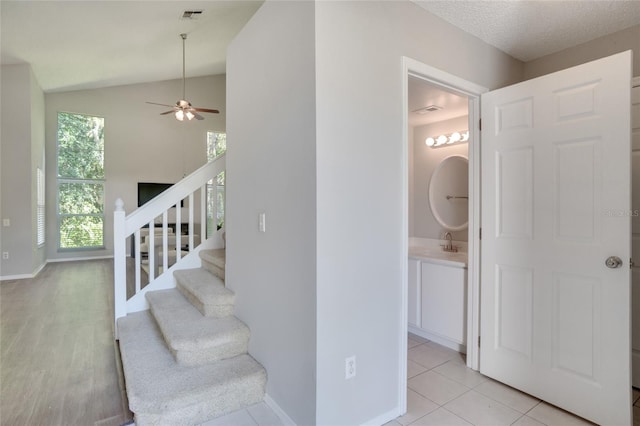 stairs featuring tile patterned floors, sink, a textured ceiling, high vaulted ceiling, and ceiling fan