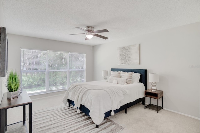 carpeted bedroom featuring ceiling fan and a textured ceiling