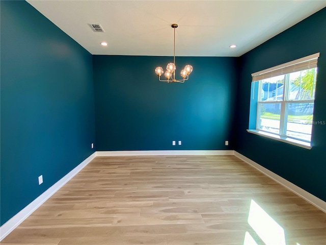 empty room featuring light hardwood / wood-style flooring and a notable chandelier