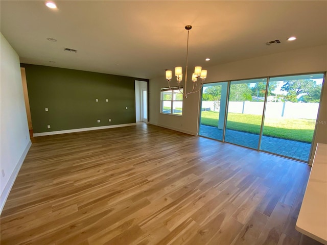 spare room featuring hardwood / wood-style floors and a chandelier