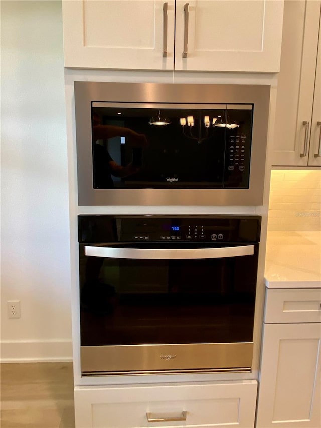 58 Overleaf Ln, Orlando, FL 32839 - kitchen view of oven, built in microwave, baseboards, white cabinets, and light countertops