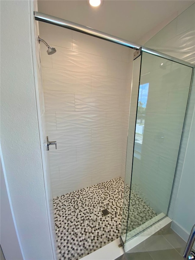 bathroom with a shower with door and tile patterned floors