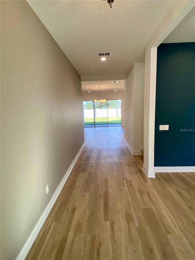 hallway with a chandelier and light hardwood / wood-style floors