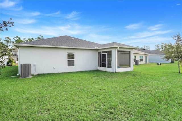 rear view of house with a yard, central air condition unit, and a sunroom