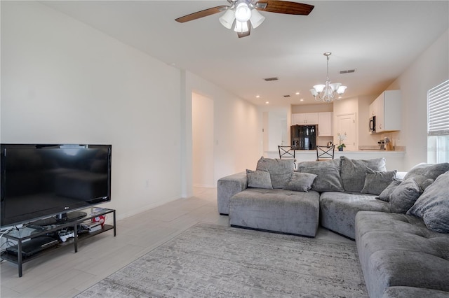 living room featuring light wood-type flooring and ceiling fan with notable chandelier