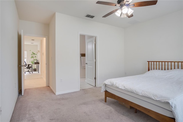 bedroom featuring ensuite bathroom, light colored carpet, and ceiling fan