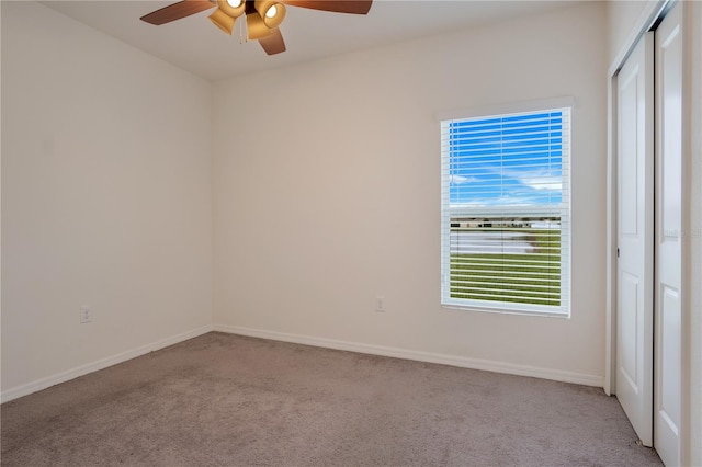 carpeted spare room featuring ceiling fan