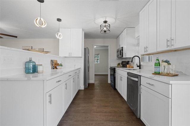 kitchen with appliances with stainless steel finishes, sink, white cabinetry, pendant lighting, and dark hardwood / wood-style floors