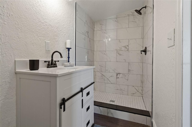 bathroom with vanity, a tile shower, and a textured ceiling