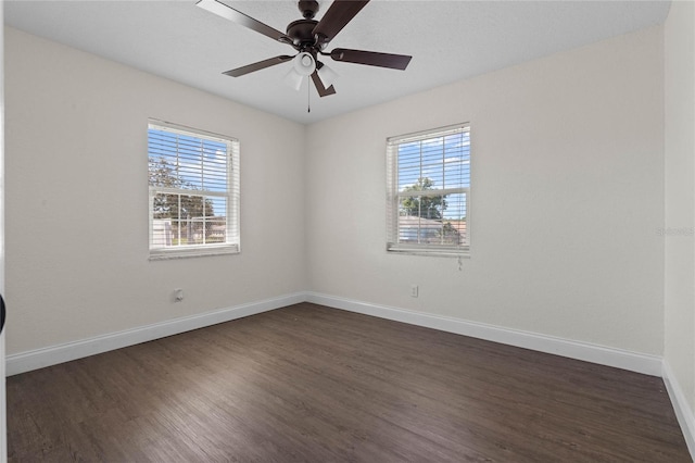 spare room featuring ceiling fan, a wealth of natural light, and dark hardwood / wood-style floors