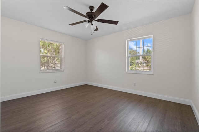 empty room with dark hardwood / wood-style floors, a healthy amount of sunlight, and ceiling fan