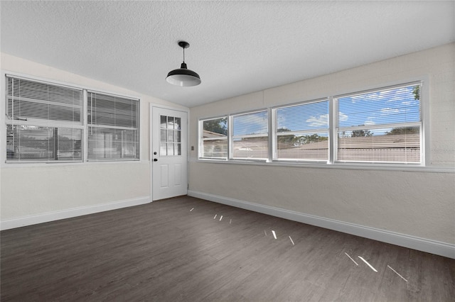 spare room featuring dark wood-type flooring, a textured ceiling, and lofted ceiling