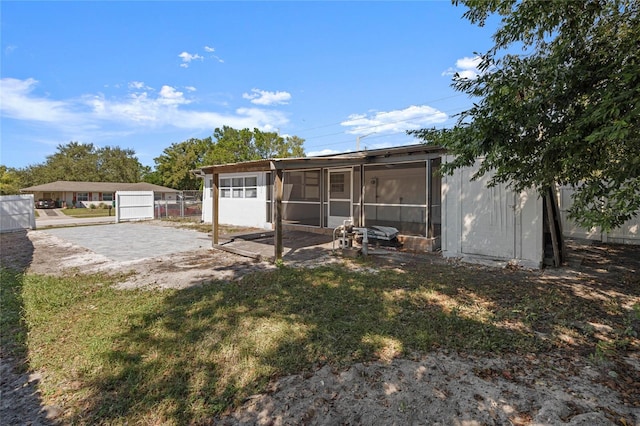 rear view of property featuring a patio, a sunroom, and a lawn