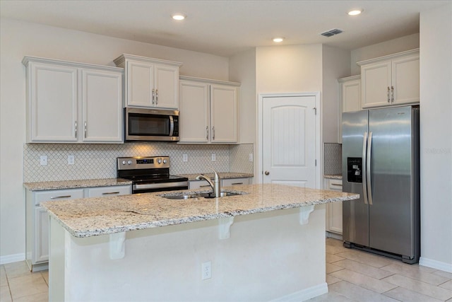 kitchen with appliances with stainless steel finishes, white cabinets, sink, and an island with sink