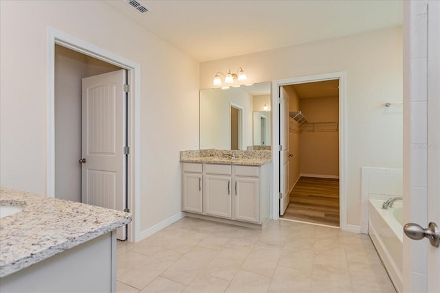 bathroom featuring vanity, a washtub, and tile patterned flooring