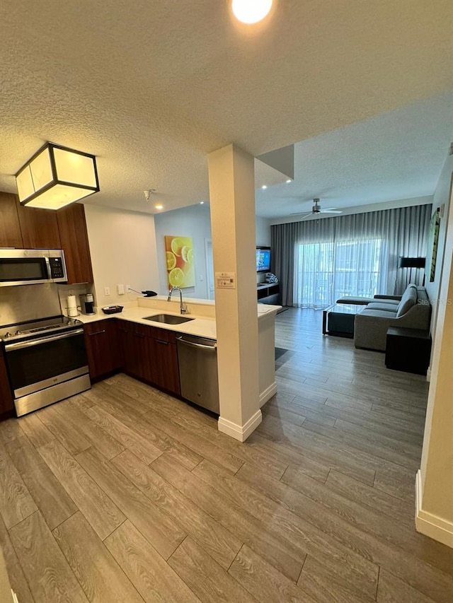 kitchen with sink, appliances with stainless steel finishes, light hardwood / wood-style flooring, and a textured ceiling