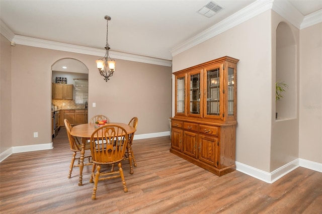 dining room featuring light wood-type flooring, ornamental molding, and a notable chandelier