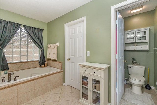 bathroom featuring tile patterned flooring, a textured ceiling, toilet, and tiled tub