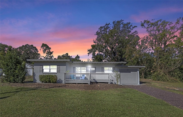 view of front of property featuring a garage, a wooden deck, and a lawn