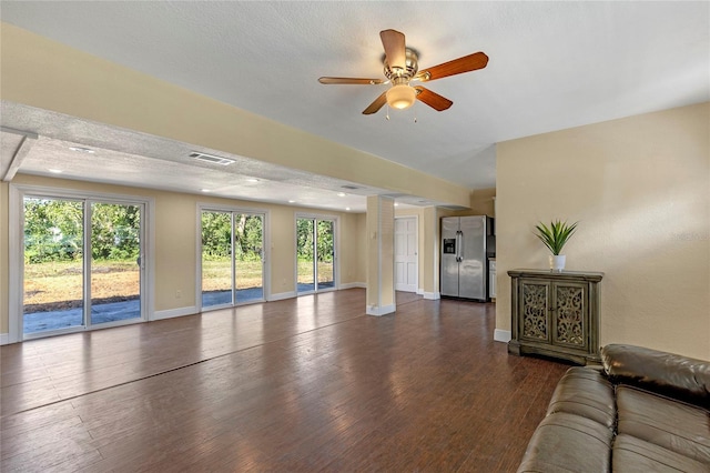 unfurnished living room featuring ceiling fan, dark hardwood / wood-style floors, a textured ceiling, and decorative columns