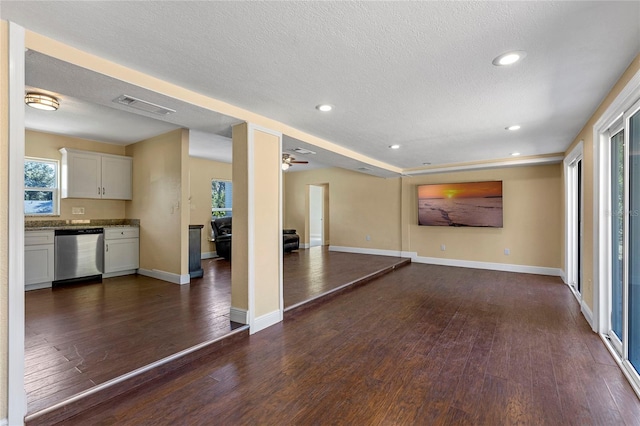 unfurnished living room with dark wood-type flooring, a textured ceiling, and ceiling fan