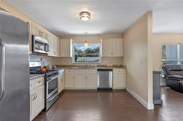 kitchen with dark hardwood / wood-style flooring, light stone countertops, pendant lighting, and appliances with stainless steel finishes