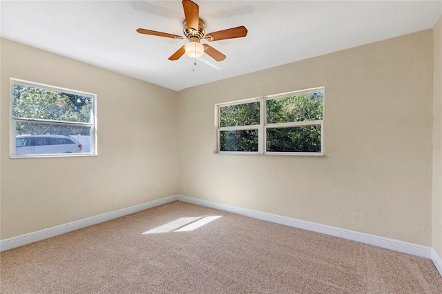 empty room featuring ceiling fan, plenty of natural light, and carpet flooring