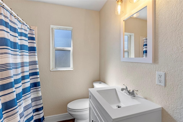 bathroom featuring toilet, vanity, and plenty of natural light