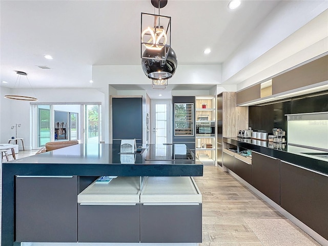 kitchen featuring decorative light fixtures, light wood-type flooring, and stainless steel oven