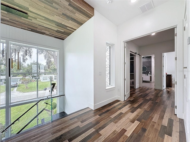 hallway with dark hardwood / wood-style floors, wooden ceiling, vaulted ceiling, and a barn door