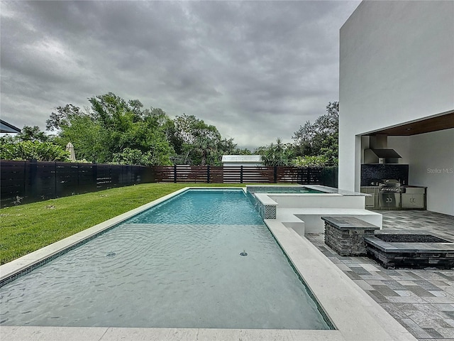 view of pool featuring a lawn and an outdoor kitchen