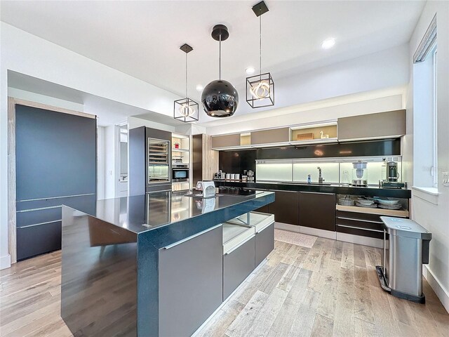 kitchen featuring a center island, pendant lighting, light hardwood / wood-style floors, and oven