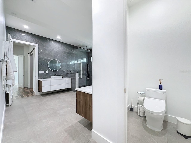 bathroom with vanity, a tile shower, toilet, and tile patterned flooring