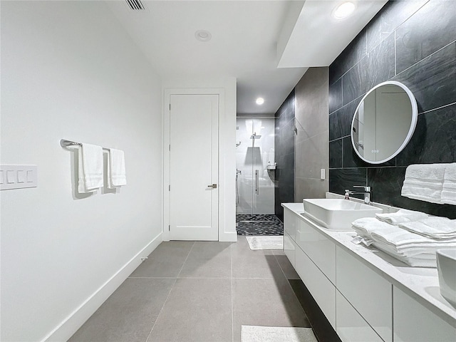 bathroom featuring vanity, a shower, tile walls, and tile patterned floors