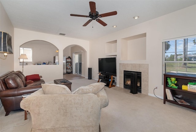 carpeted living room with a tile fireplace and ceiling fan