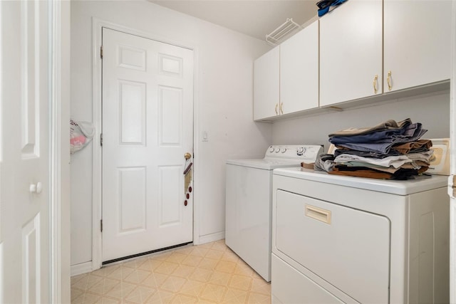 clothes washing area featuring cabinets and washing machine and dryer