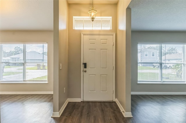 foyer entrance with a chandelier and dark wood-type flooring