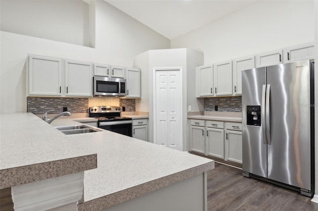 kitchen featuring appliances with stainless steel finishes, sink, a kitchen breakfast bar, dark wood-type flooring, and kitchen peninsula