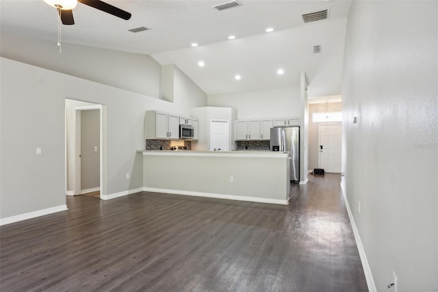 kitchen with white cabinetry, kitchen peninsula, dark hardwood / wood-style flooring, tasteful backsplash, and appliances with stainless steel finishes