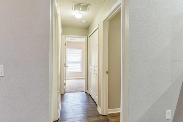 hallway featuring dark hardwood / wood-style flooring and a textured ceiling