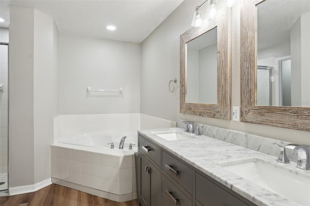 bathroom featuring hardwood / wood-style floors, separate shower and tub, vanity, and a textured ceiling