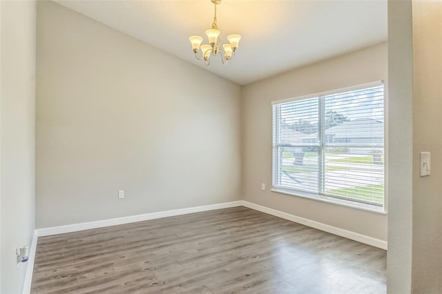 unfurnished room featuring an inviting chandelier and wood-type flooring