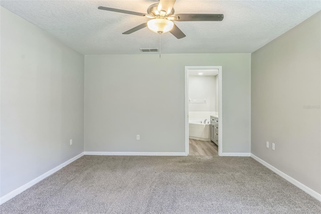 carpeted spare room featuring ceiling fan and a textured ceiling