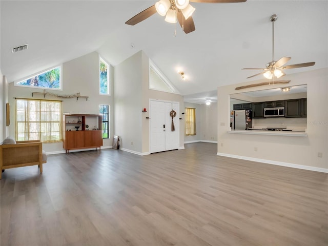 unfurnished living room with high vaulted ceiling, light wood-type flooring, and ceiling fan