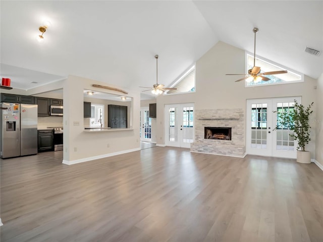 unfurnished living room featuring a wealth of natural light, french doors, high vaulted ceiling, and light hardwood / wood-style floors