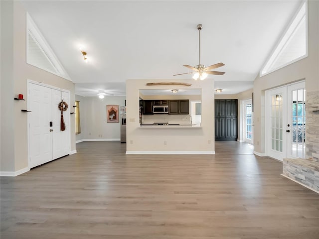 unfurnished living room featuring french doors, light hardwood / wood-style flooring, vaulted ceiling, and ceiling fan