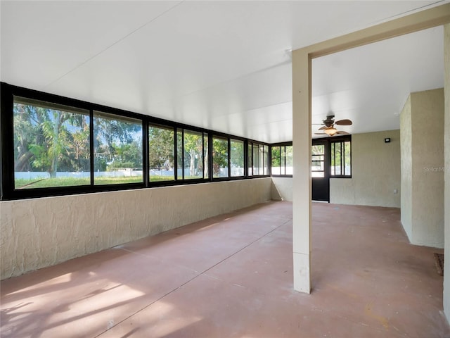 unfurnished sunroom featuring ceiling fan and a healthy amount of sunlight