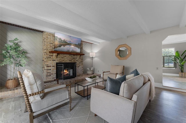 living room with beamed ceiling, dark wood-type flooring, a fireplace, and wooden walls