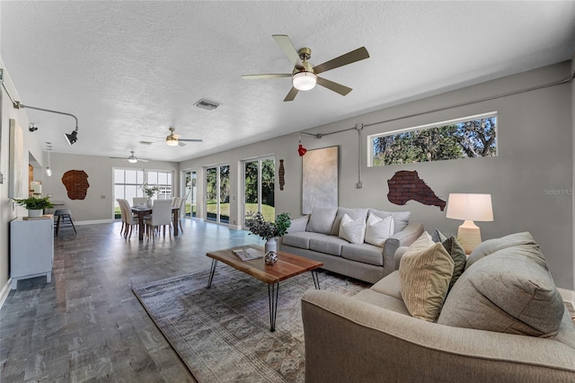 living room with ceiling fan, a textured ceiling, and dark hardwood / wood-style floors